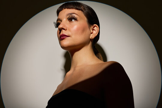 Model poses against a circular backdrop lit in a studio setting