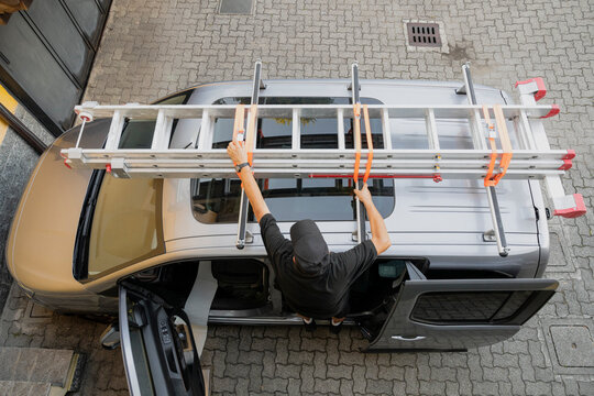 Handyman Securing Extension Ladder on Van Roof Rack