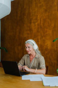Senior woman typing with headphones
