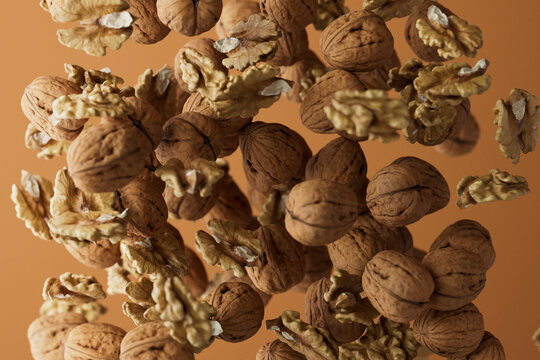 Floating Walnuts and Walnut Pieces on Brown Background