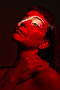Woman with red face paint posing in dark setting at night