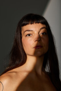 Woman with long dark hair and blunt bangs in natural light