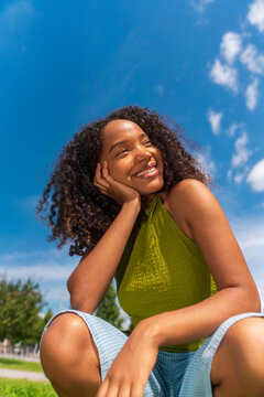 Young woman Smiling outdoors with hand resting on face