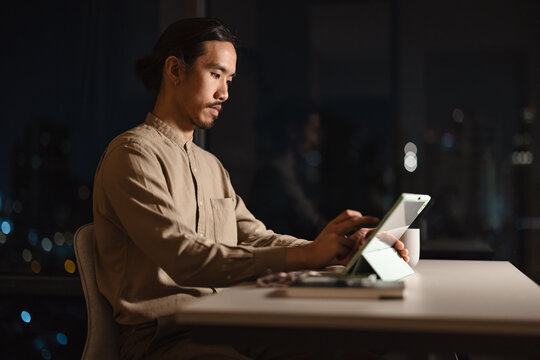 Man Working on Tablet in Office at Night