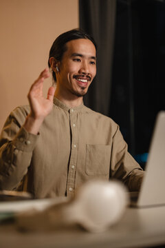 Man Smiling and Waving While Video Calling From a Home Office