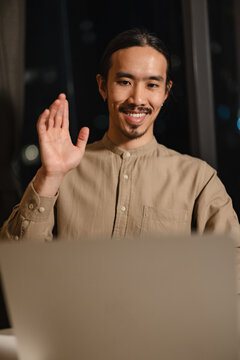 Man Waves While Video Chatting at Home in Evening