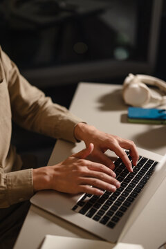 Person Typing on a Laptop at a Desk in a Dimly Lit Room