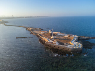 Aerial early morning view of San Sebastian Castle on an island surrounded by the Atlantic Ocean, featuring a long stone bridge leading to the city and the urban skyline emerging through morning mist.  © nzatravel