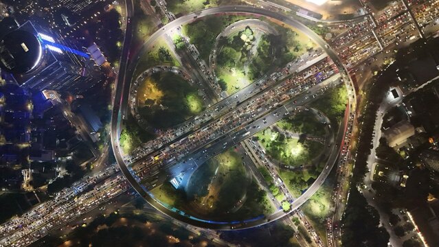 Aerial view of the Semanggi interchange at night, featuring illuminated cloverleaf roads and heavy traffic flow in Jakarta Selatan, DKI Jakarta, Indonesia.