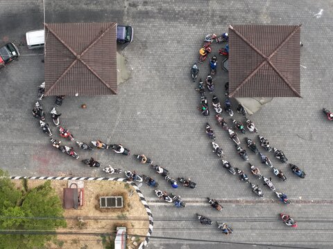 Aerial view of a long queue of motorcycles waiting at the Pertamina gas station 54.803.08 in Kecamatan Mengwi, Bali, Indonesia.