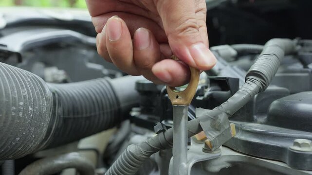 Close-up of a technician checking the engine oil level by pulling the dipstick, a crucial step in automotive diagnostics and preventive vehicle maintenance.