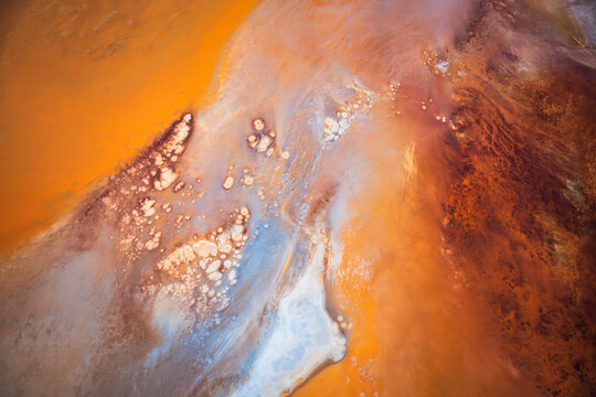 Aerial view of the vibrant mineral-rich waters and salt crusts of the Great Salt Lake, showcasing striking orange, red, and blue patterns in Salt Lake City, Utah, United States.