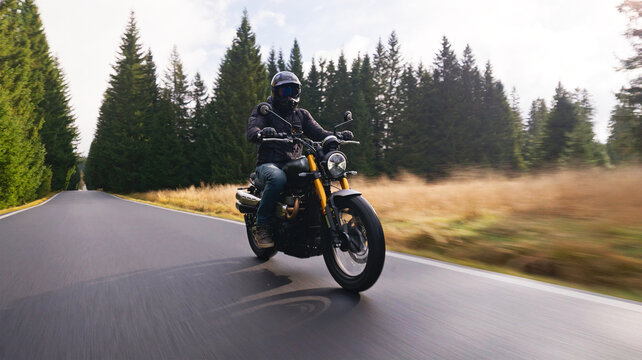 A rider on a stylish retro motorcycle travels along a paved forest road in the evening. Shot in motion with a panning camera, the blurred asphalt and soft dusk light create a dynamic sense of speed.