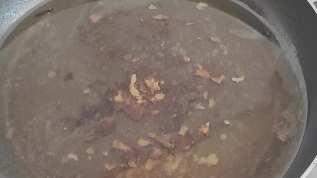 Close up top view of small pieces of meat and garlic frying in hot, bubbling oil. A delicious and savory cooking process for a meal