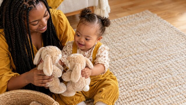 Mother and toddler playing with stuffed bunny toys together on living room rug. Family bonding and affectionate childcare. Parent and child at home. Cozy childhood playtime with copy space.