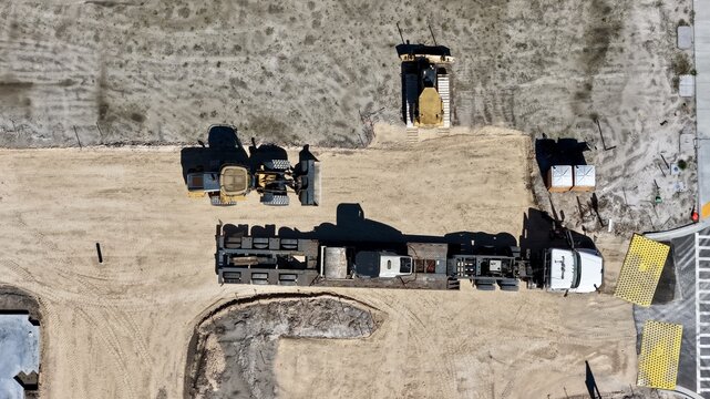 Aerial view of construction equipment including a bulldozer and a flatbed truck on a dirt site near Foundry Lane and International Golf Parkway, World Golf Village, Florida, United States.