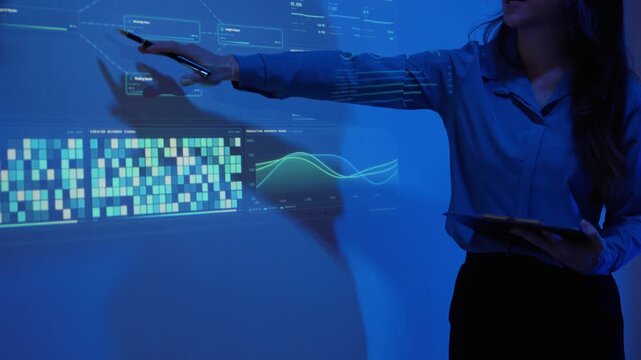 Businesswoman presenting data analysis and futuristic flowchart on a screen during a corporate meeting in a dark room