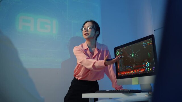 Female data scientist presenting AGI project showing neural network data on a computer screen in a futuristic office at night