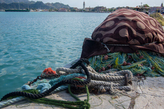 Fishermans equipment lying on the coastline in harbor, heap nylon yellow tangled fishing net in sunlight, colorful ropes
