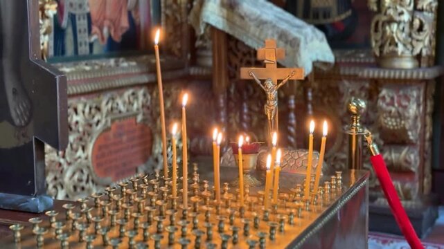 Orthodox church candle stand with glowing flames and crucifix, ornate religious interior, devotional worship setting, warm spiritual atmosphere, sacred heritage background and copy space for