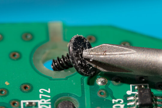 Close-up of screwdriver tightening a screw on a circuit board