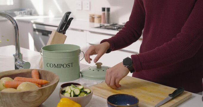 Compost lid being set aside as metal peeler is peeling potato and collecting skins for cooking