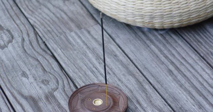 Woven cushion sliding down from upper right, covering incense holder as smoke is rising on deck