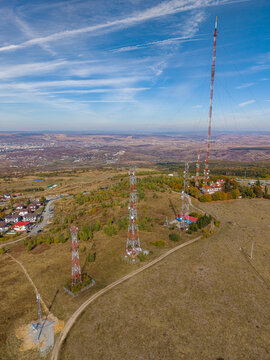 Aerial view of Feleacu 311A Cluj telecommunication towers on a grassy hill with autumn foliage and a distant city view in Cluj-Napoca, Judetul Cluj, Romania.