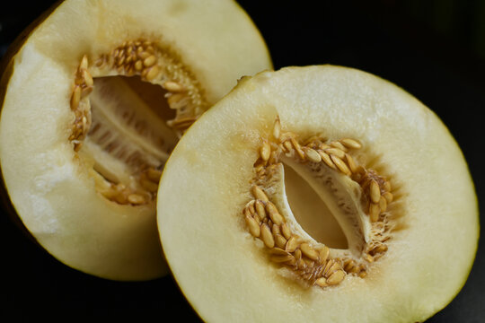 Two half yellow melon on black background. Sweet organic melon cut of half with seeds. Food and fruit background, Health , vitamins concept.