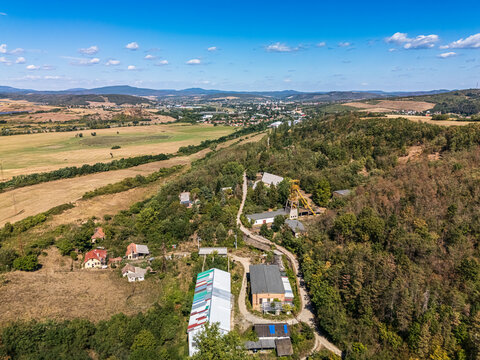 Aerial view of a former coal mine headframe and industrial buildings amid forest, farmland and rolling hills near Batonyterenye, Hungary, in the Nograd coal basin.