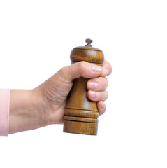 Female hand holding wooden pepper mill on isolated background. © nndanko