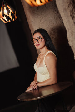 Photoshoot of a beautiful young Latina woman wearing glasses in a bar.
