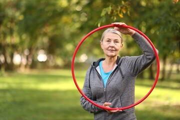 Senior woman with hula hoop in park, space for text © New Africa