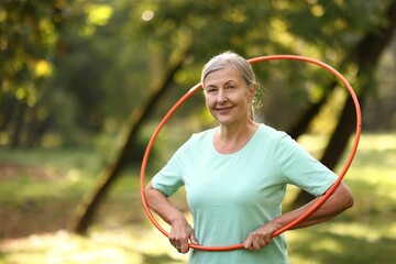 Senior woman with hula hoop in park, space for text © New Africa