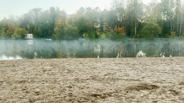 POV walkthrough of an empty sandy beach, shot on stabilizer. Smooth forward camera motion, no people. A peaceful, misty lake in Pushkin, Russia moves gently in slow motion.