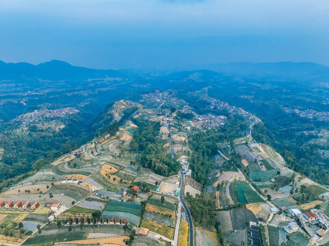 Aerial view of Linggarjati 2 featuring terraced agricultural fields, winding roads, and small buildings nestled in the mountains of Kecamatan Kaliangkrik, Jawa Tengah, Indonesia.