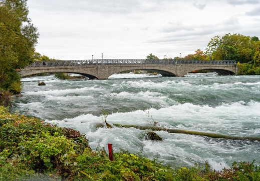 Niagara Falls, United States - 10 October 2026: View of the Niagara River flowing under a stone arch bridge with lush autumn foliage along the banks.