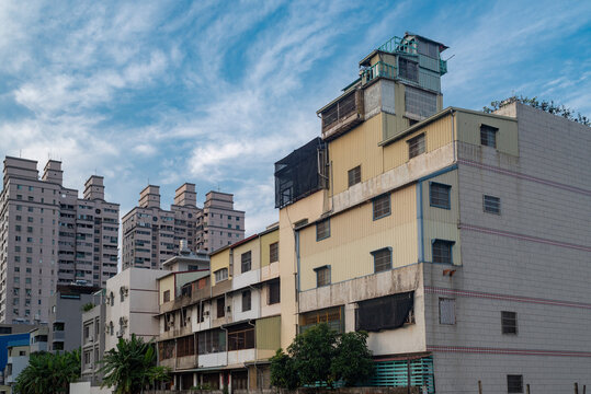 Tainan, Tainan City, Taiwan - 12 May 2015: View of older residential buildings with varied architectural additions and metal roofing, contrasted with modern high-rise towers under a blue sky.