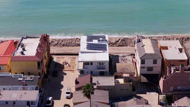 Long Beach, California, USA - October 15, 2026: Flight right to left over homes behind a tall sand berm built to shield the Peninsula from high surf and flooding after Tropical Storm Rachel.