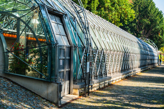 Prague, Prague, Czechia - 05 October 2026: View of the modern glass greenhouse structure with metal framework and cobblestone path in the botanical garden.