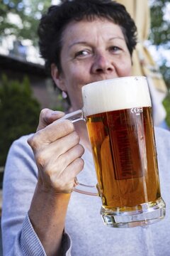 Woman (50-55) with a glass of beer in a beer garden, Prague, Bohemia, Czech Republic