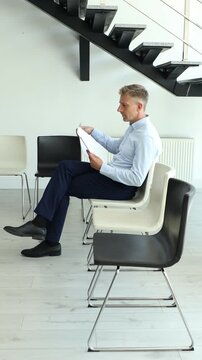 Man with documents waiting for job interview on chair indoors