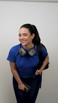 Confident latina female student with a backpack and laptop smiling isolated on a white background