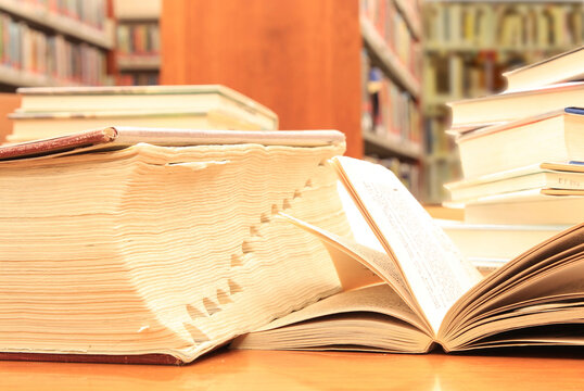 Thick Reference Book and Open Volume on a Library Desk