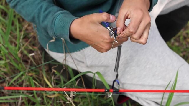 Vertical stock footage of angler using tool pliers to adjust fishing rig line