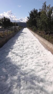 Vertical stock footage of straight concrete hydroelectric discharge channel with rushing white water torrent