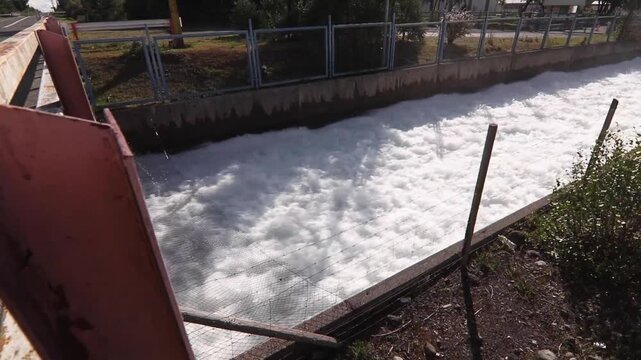 Stock footage of reinforced concrete hydroelectric spillway channel with rushing foamy water