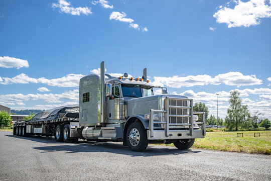 and covered loaded cargo on flat bed semi trailer standing on the local road in business area waiting right time to route start