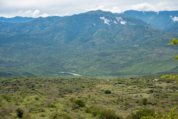 Expansive green mountain range and valley landscape, featuring lush vegetation, a winding river, and a cloudy sky, evoking themes of nature, environment, and tranquility © VICTOR A ARGUELLO