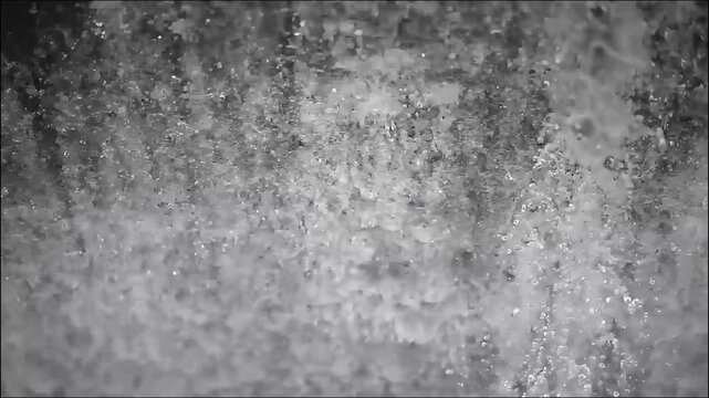 Slow motion close-up of crystal clear water flowing and creating powerful white foam splashing surface